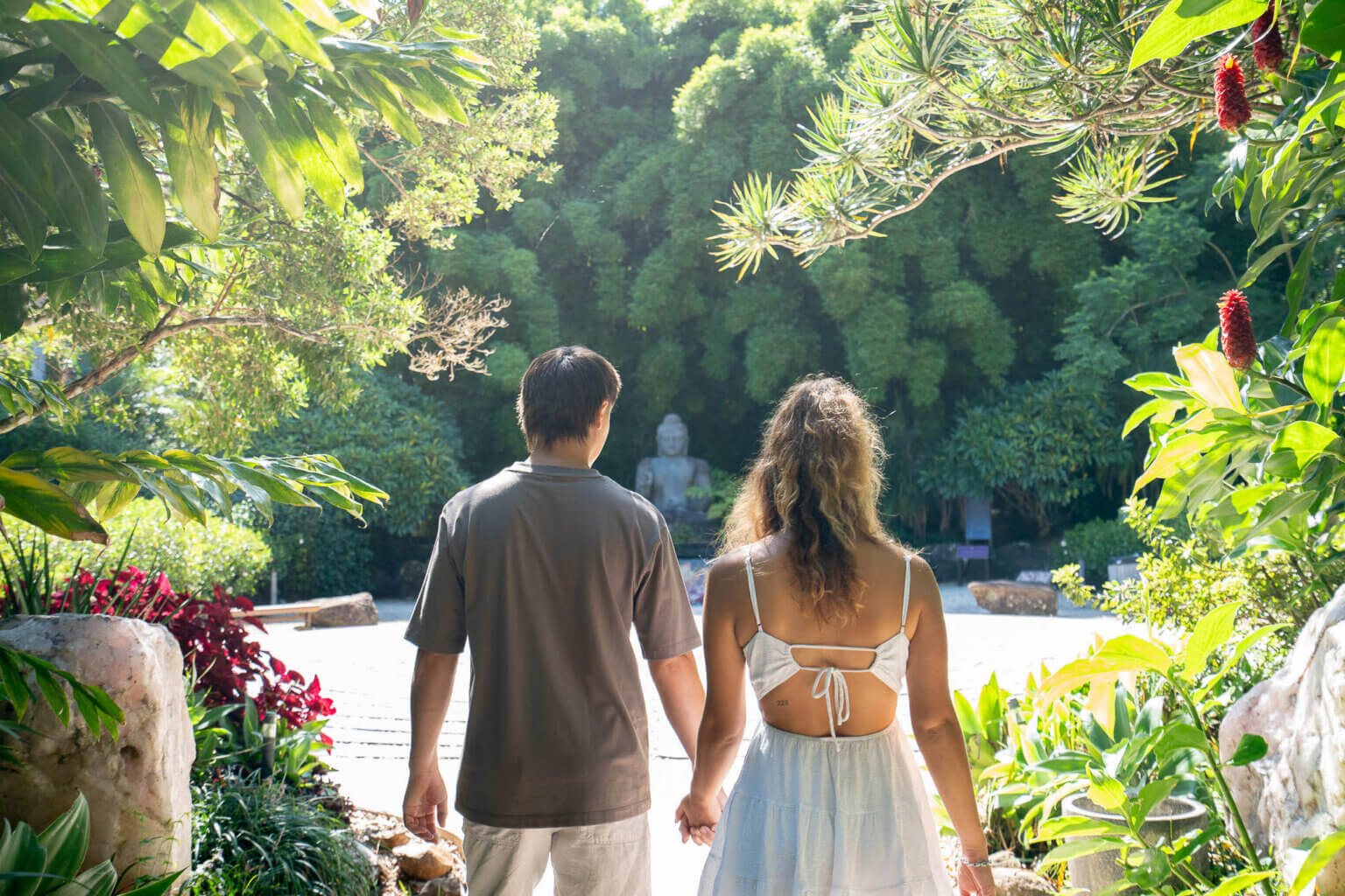 Couple walking the garden path toward the seated Buddha